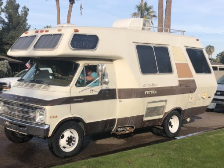 Older Chinook RV in a driveway with a happy driver