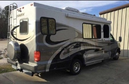 Side-entrance Chinook RV by a garage